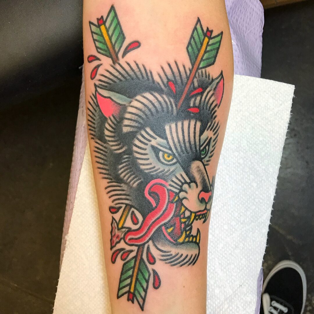 A tattoo of a cat with leaves and a snake.