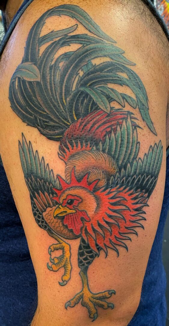 A rooster tattoo on the arm of a person.