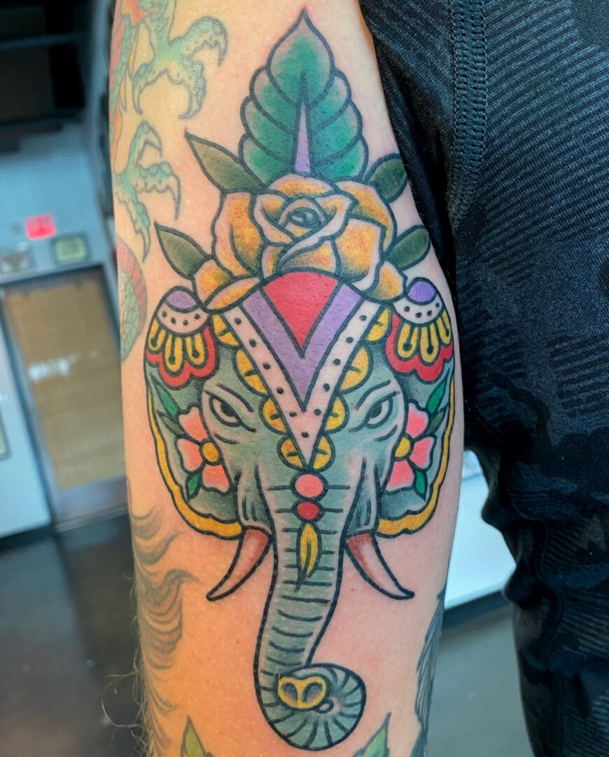A tattoo of an elephant with a rose on it's head.