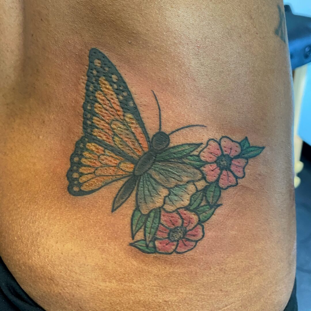 A butterfly with flowers on the side of a woman 's arm.