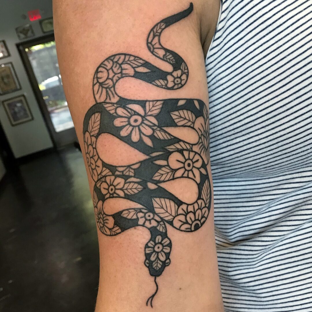 A snake tattoo with flowers on the arm