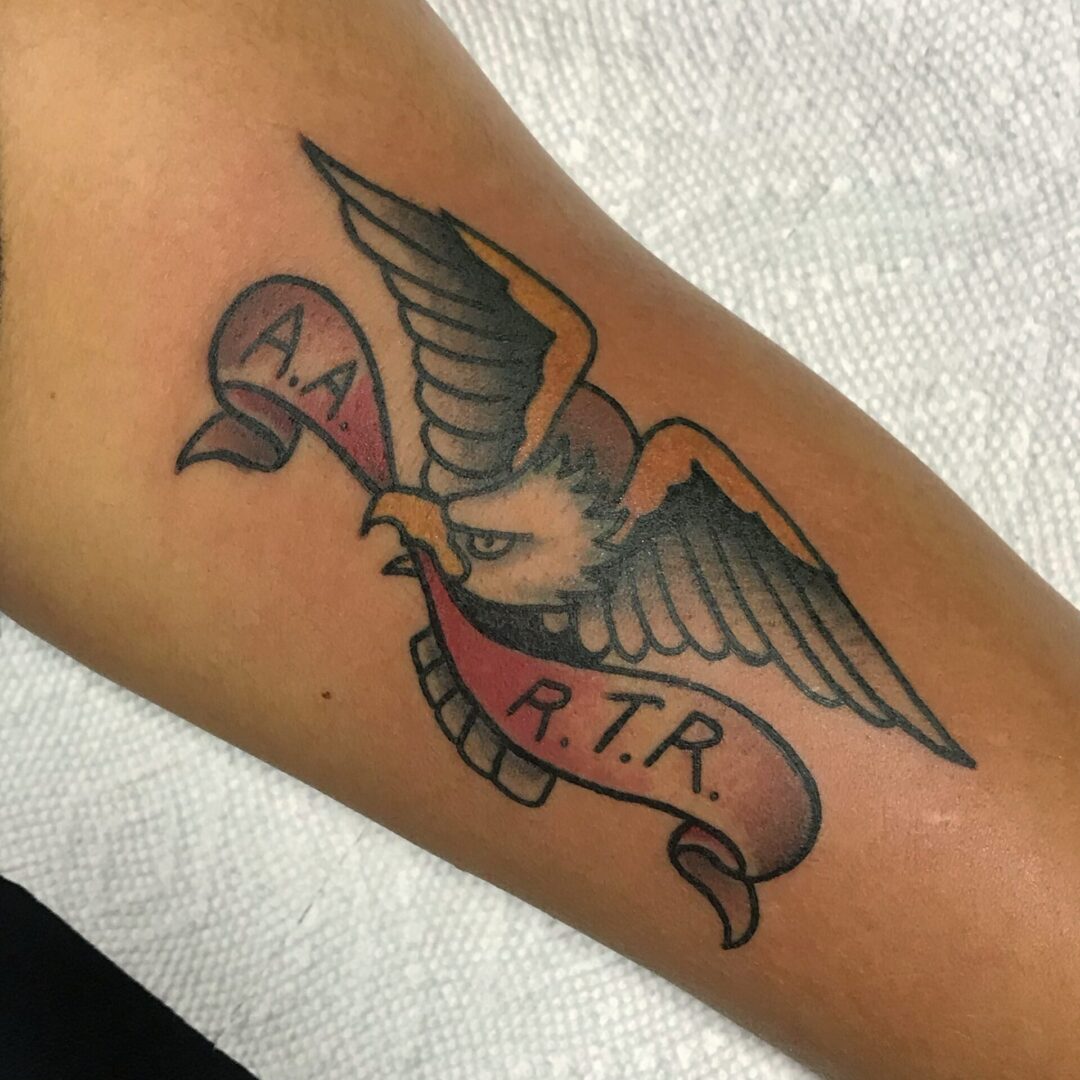 A bird with a banner and initials on it's arm.