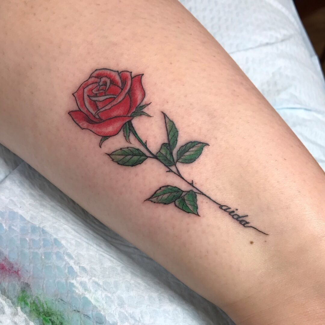 A red rose with green leaves on the arm.
