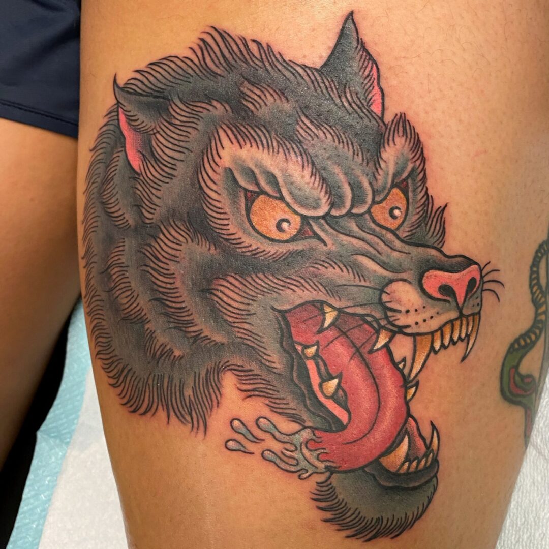 A tattoo of a wolf with its mouth open.