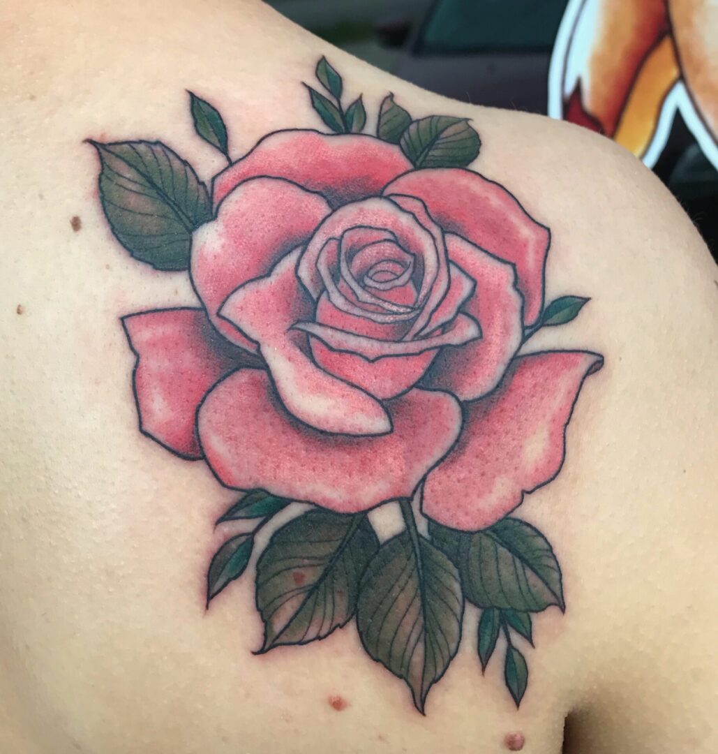 A rose tattoo on the back of someone 's shoulder.