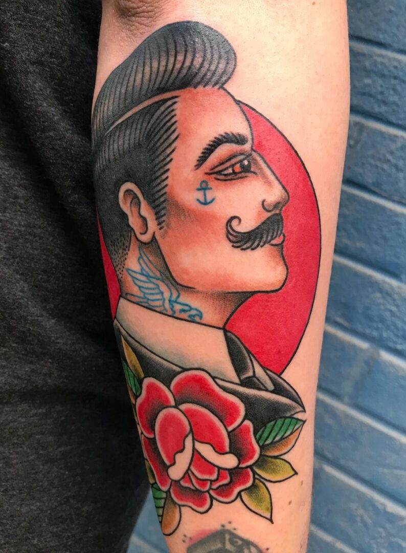 A man with a mustache and a rose tattoo on his arm.