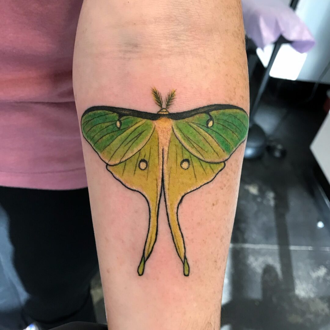 A green and yellow butterfly tattoo on the arm.