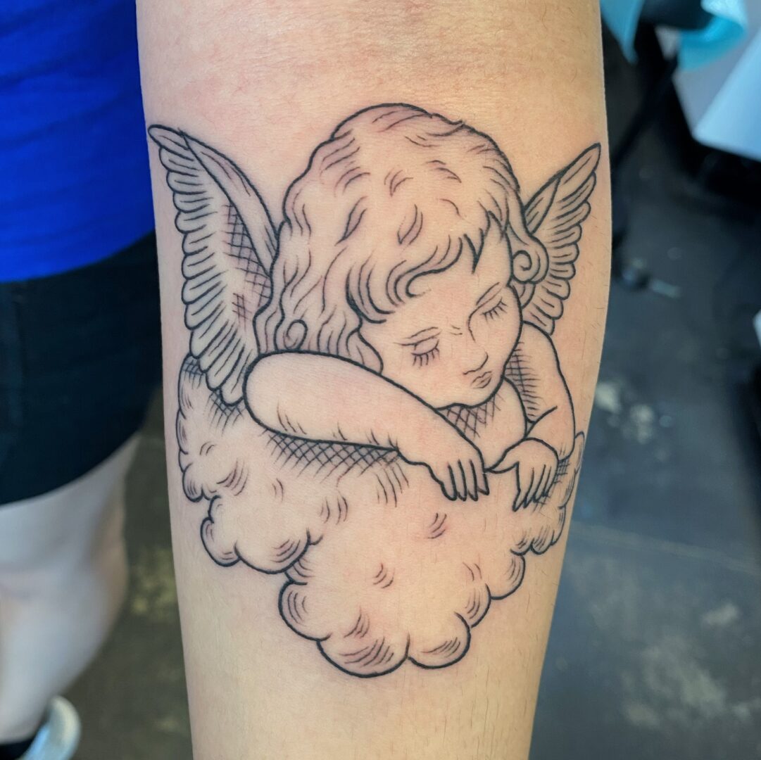 A tattoo of an angel sitting on top of a cloud.
