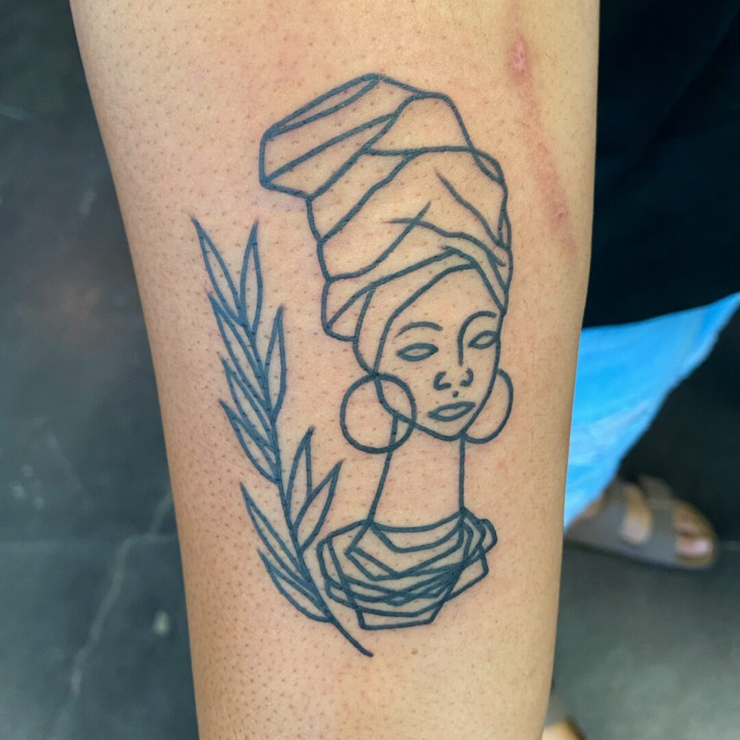 A black and white tattoo of a woman 's head with a turban.
