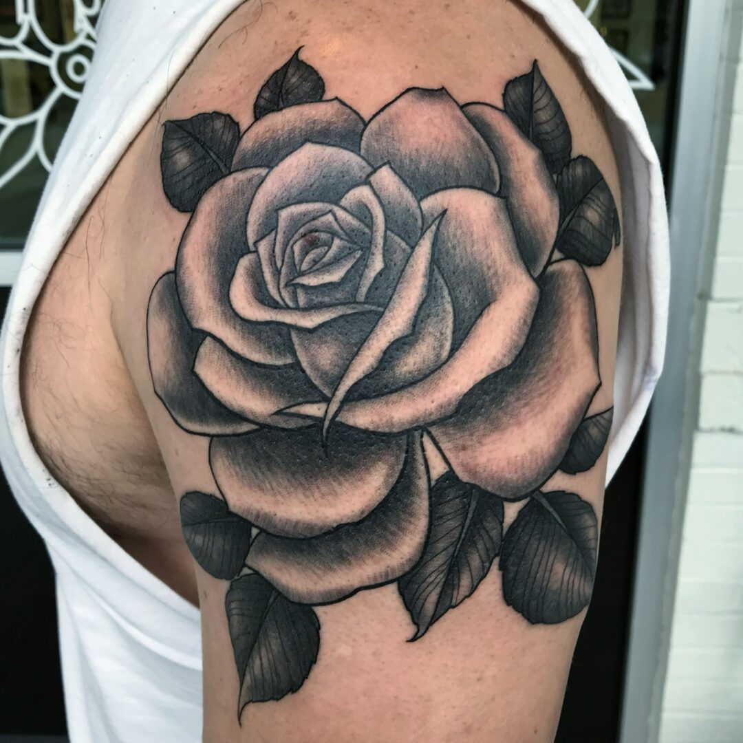A black and white rose tattoo on the shoulder