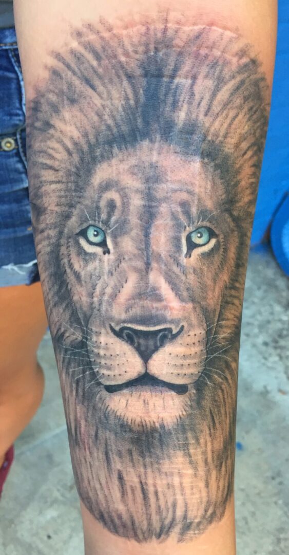 A lion tattoo with green eyes on the arm.
