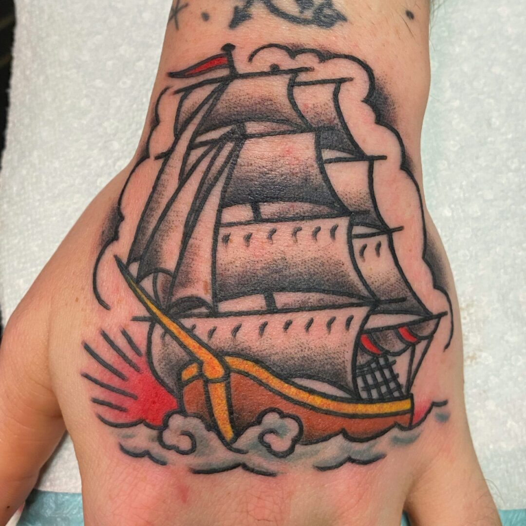 A hand with a tattoo of a ship on it