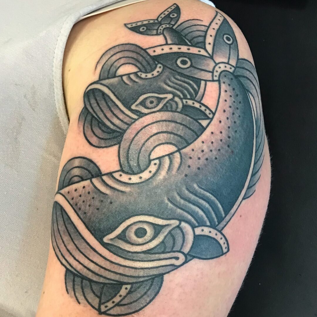 A tattoo of two fish with one bird on top.