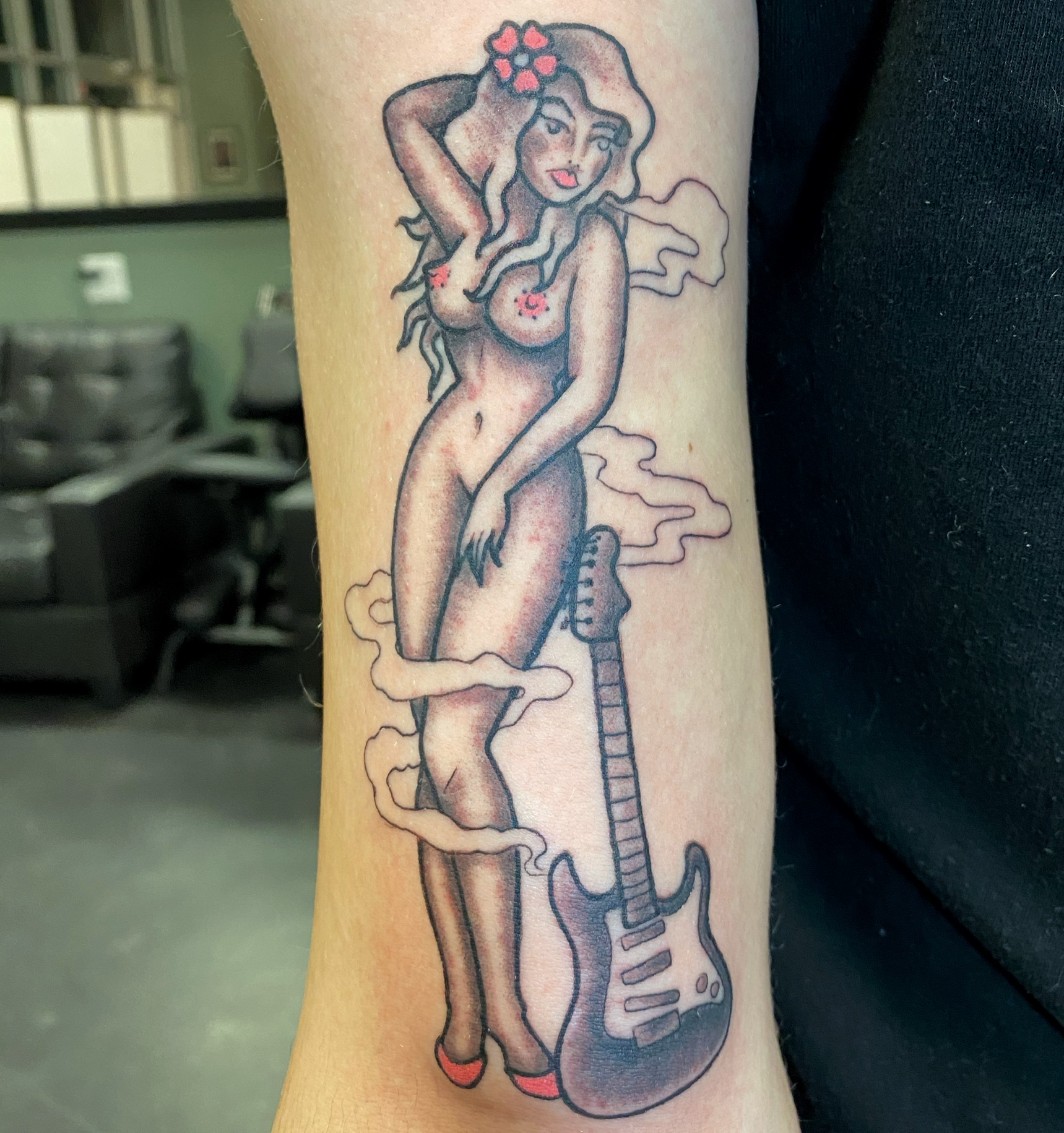 A woman with a guitar tattoo on her arm.