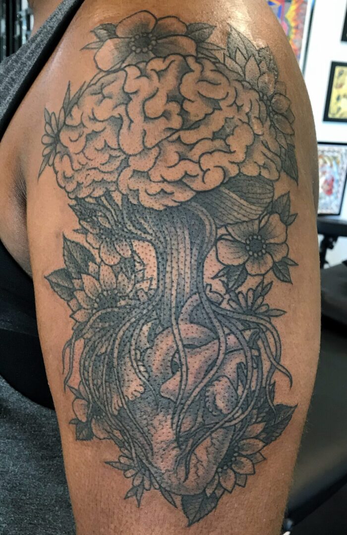 A tattoo of a tree with flowers and leaves.