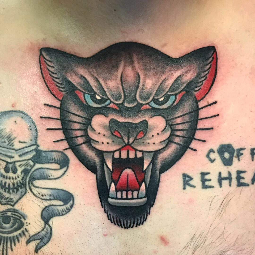 A tattoo of a cat with a snake and skull on it.