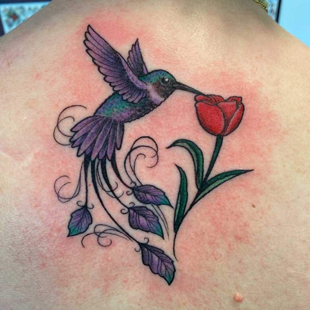 A hummingbird with flowers and leaves on the back of her body.