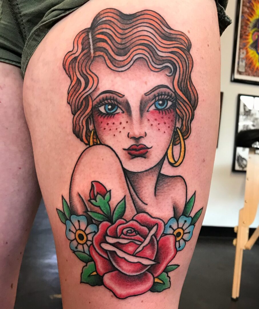 A woman with red hair and a rose tattoo on her leg.