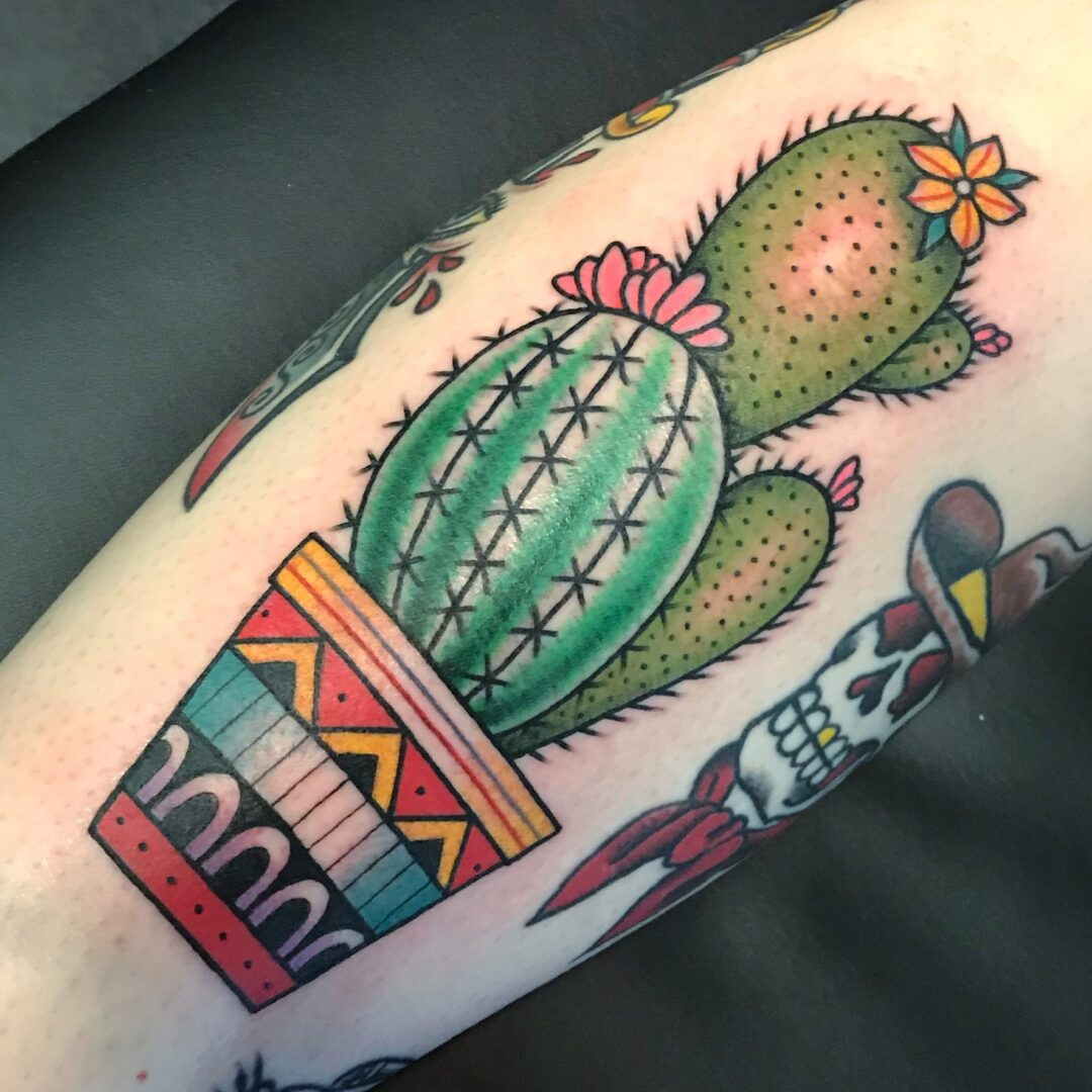 A cactus tattoo is shown on the arm.