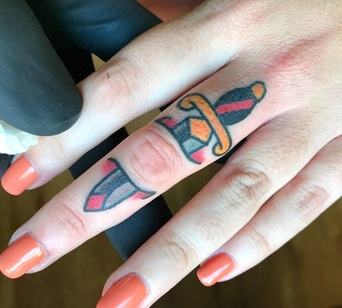 A person with their finger tattoo is holding it up.