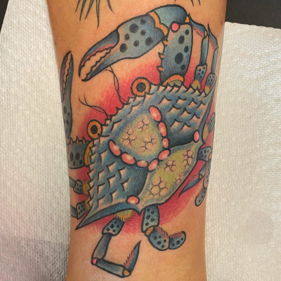 A crab tattoo is shown on the arm.