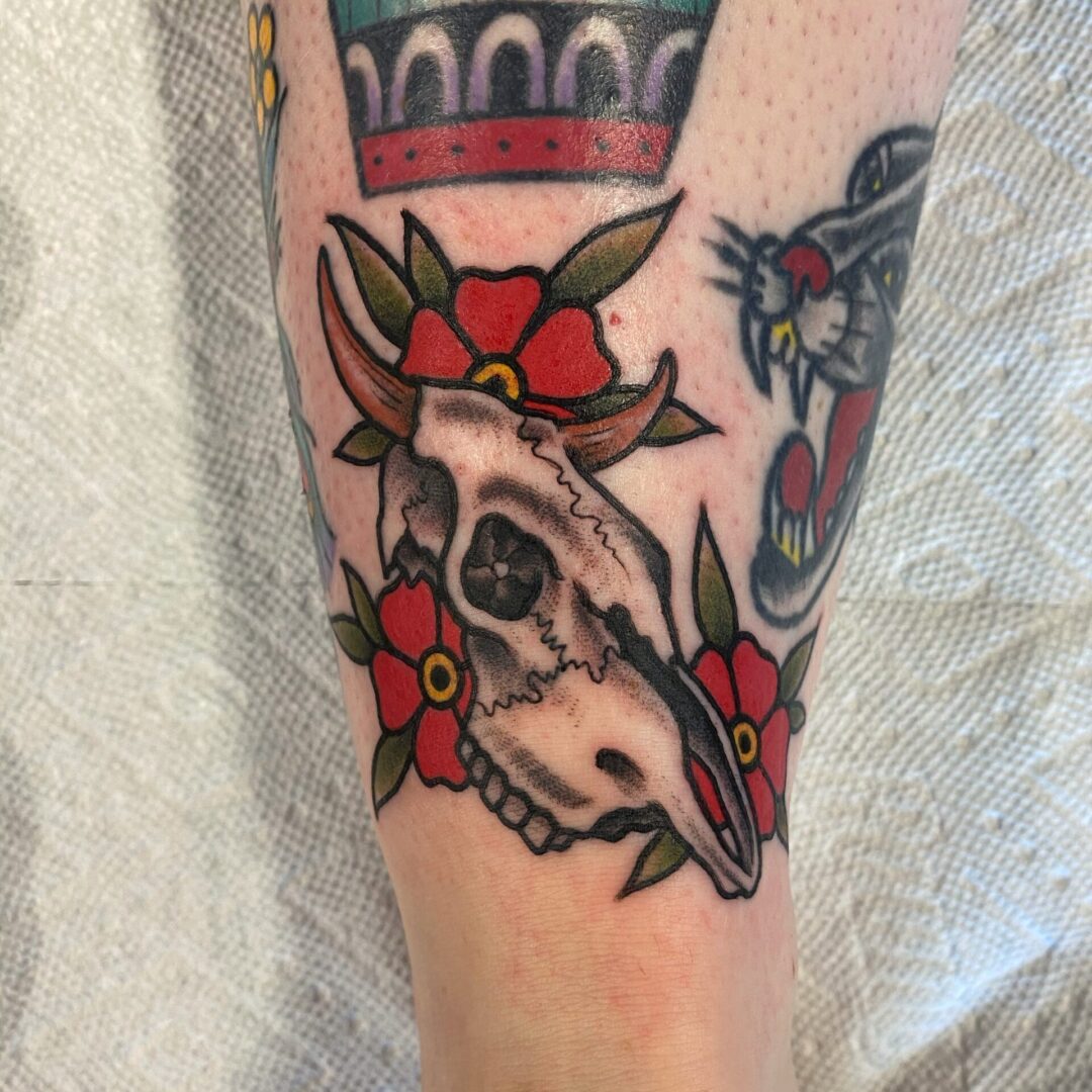 A tattoo of a cow skull with flowers and crown.