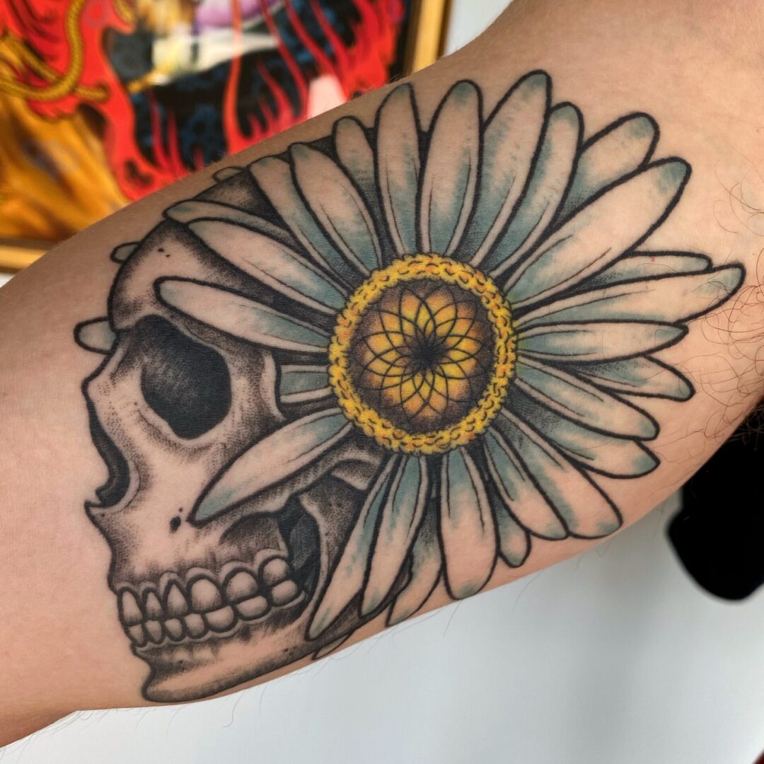 A skull with a flower on it's arm.