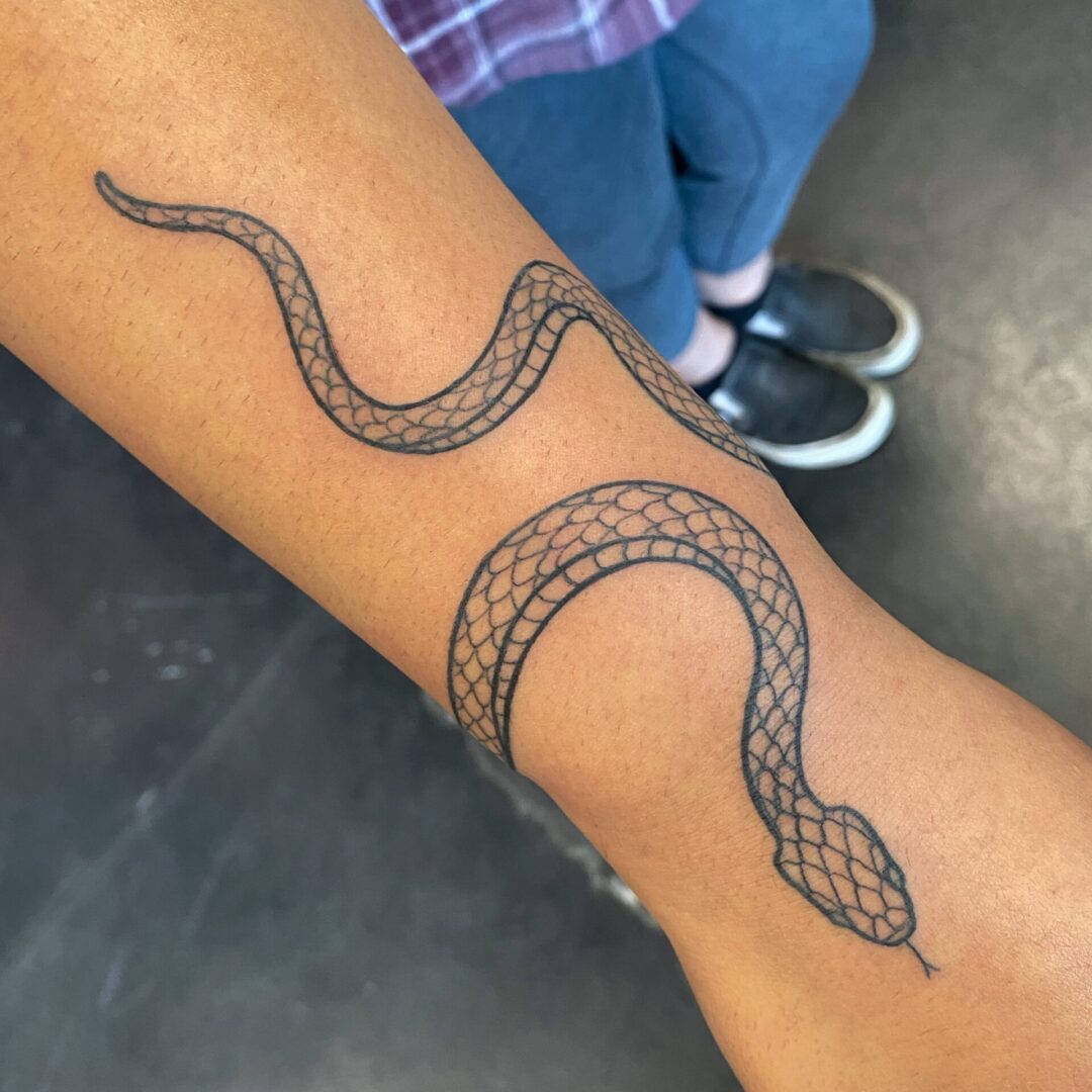 A snake tattoo is shown on the arm.
