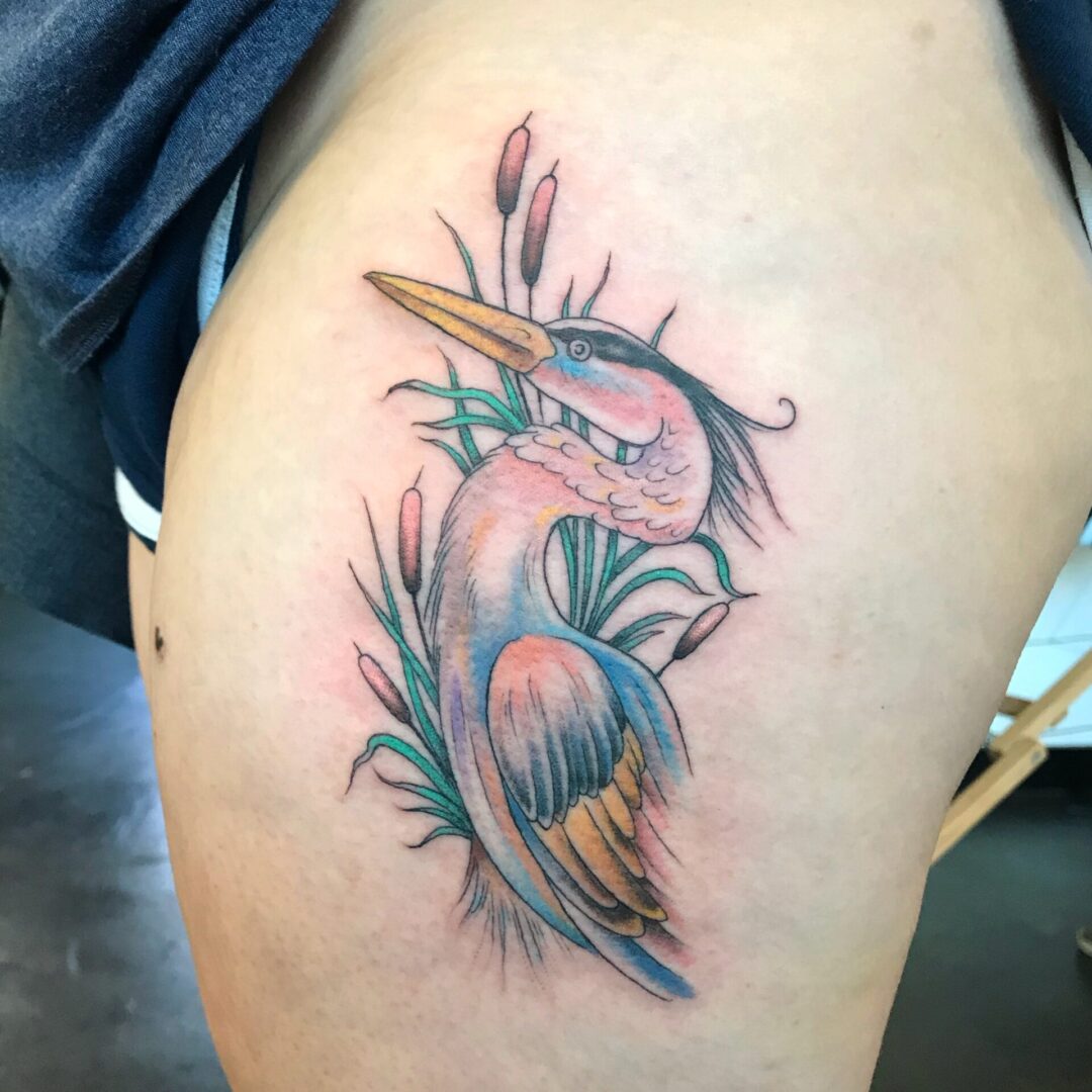 A bird sitting on top of grass tattoo.