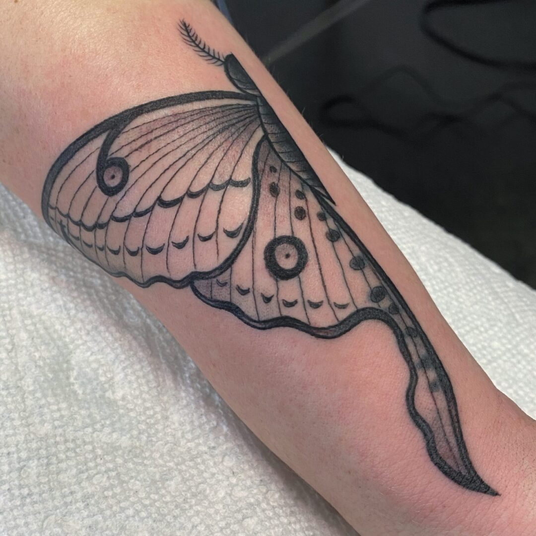 A butterfly tattoo is shown on the arm.