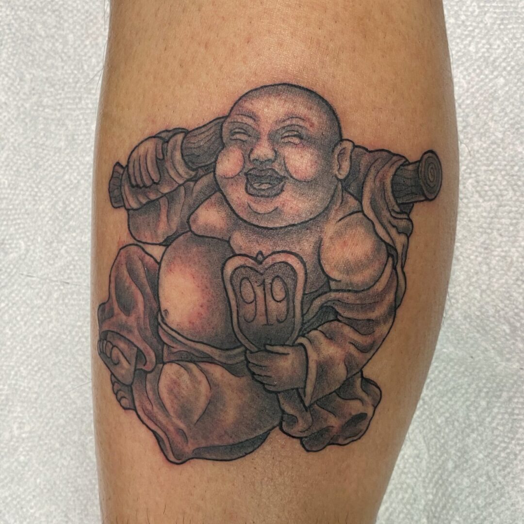A tattoo of a buddha sitting on top of a rock.