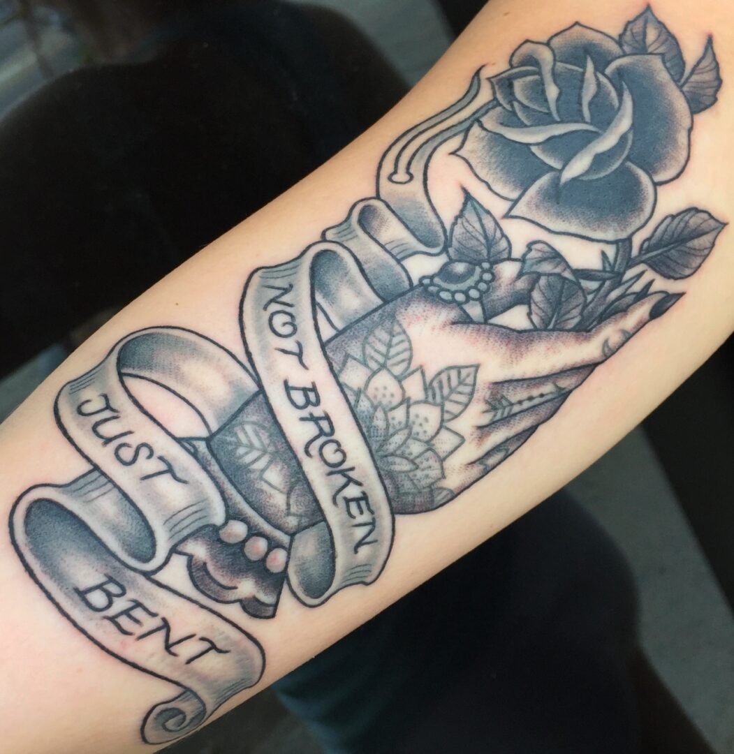 A tattoo of a cat and rose with the words 