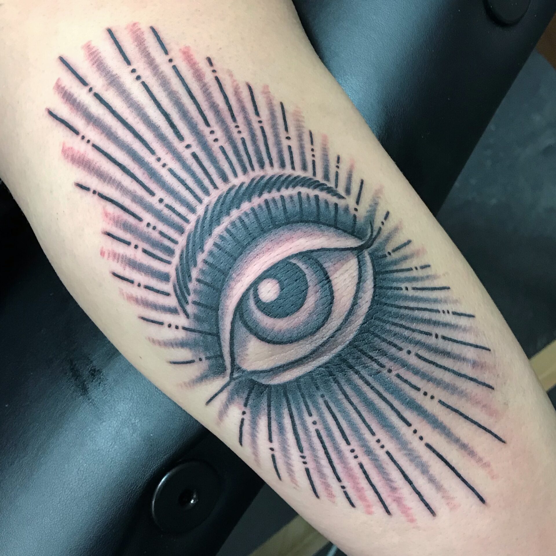 A tattoo of an eye with rays coming out it.