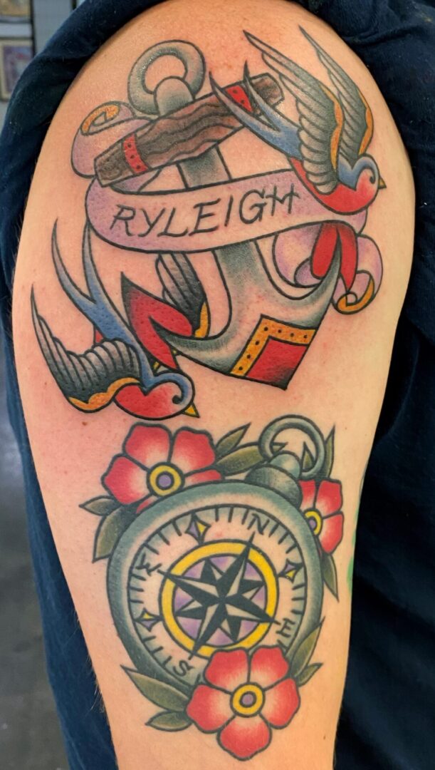 A tattoo of an anchor, compass and flowers.