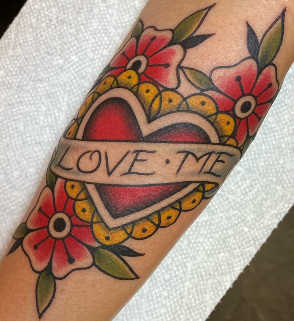 A tattoo of a heart with flowers and the word 