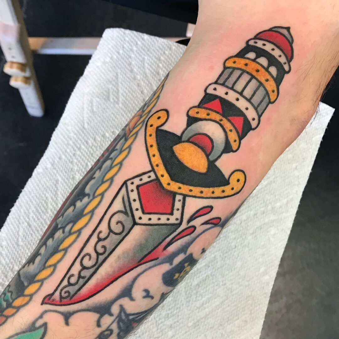 A tattoo of a lighthouse and sword on the arm.