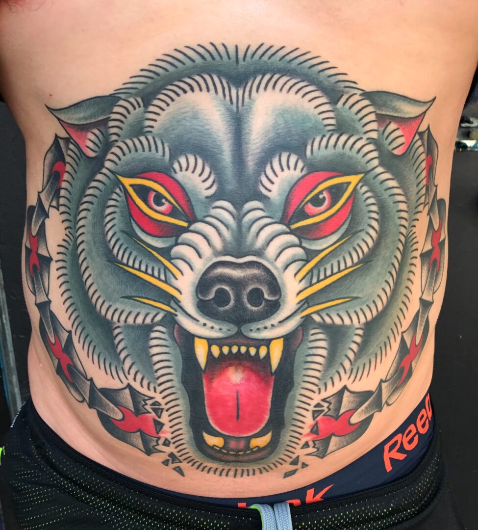 A tattoo of a wolf 's head with red eyes.