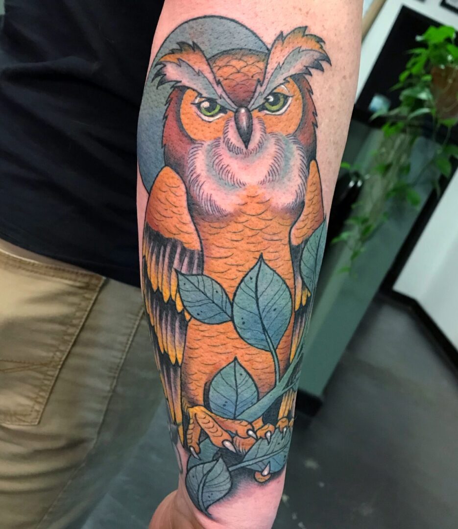 A tattoo of an owl with leaves on it.