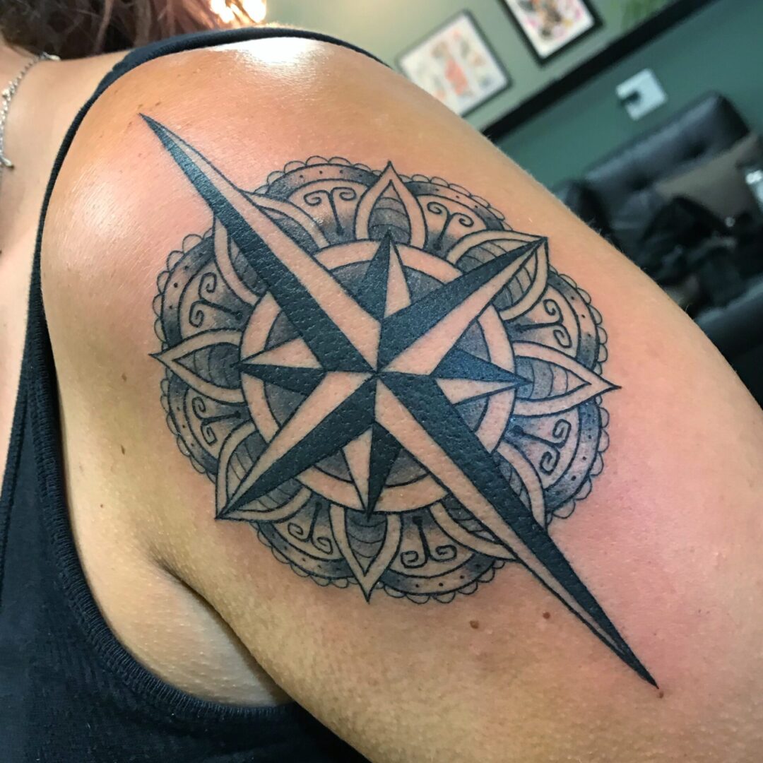 A woman with a tattoo on her shoulder of a compass.