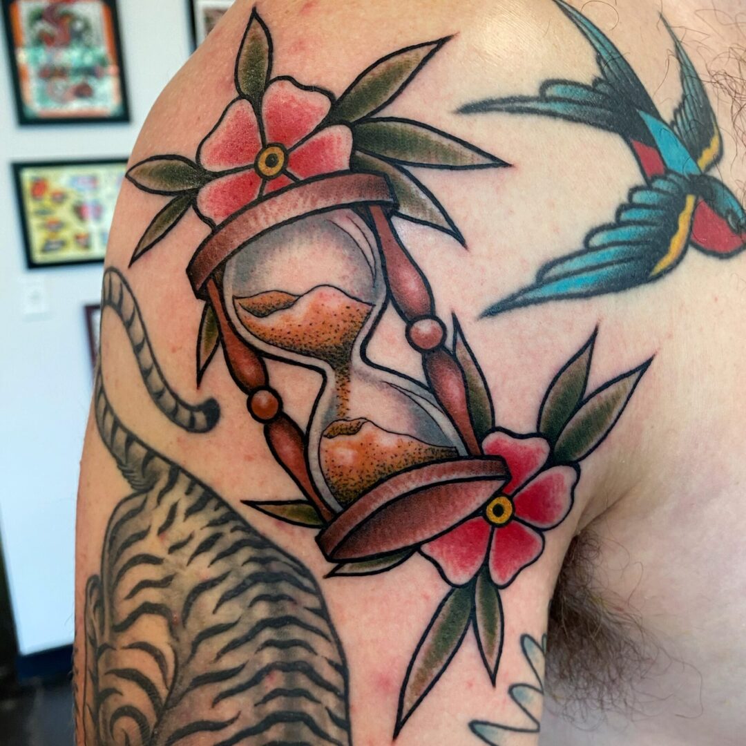 A tattoo of an hourglass sitting on top of another flower.