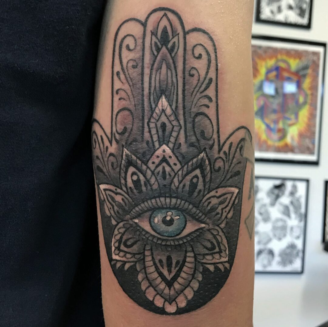 A black and white tattoo of an eye on the arm