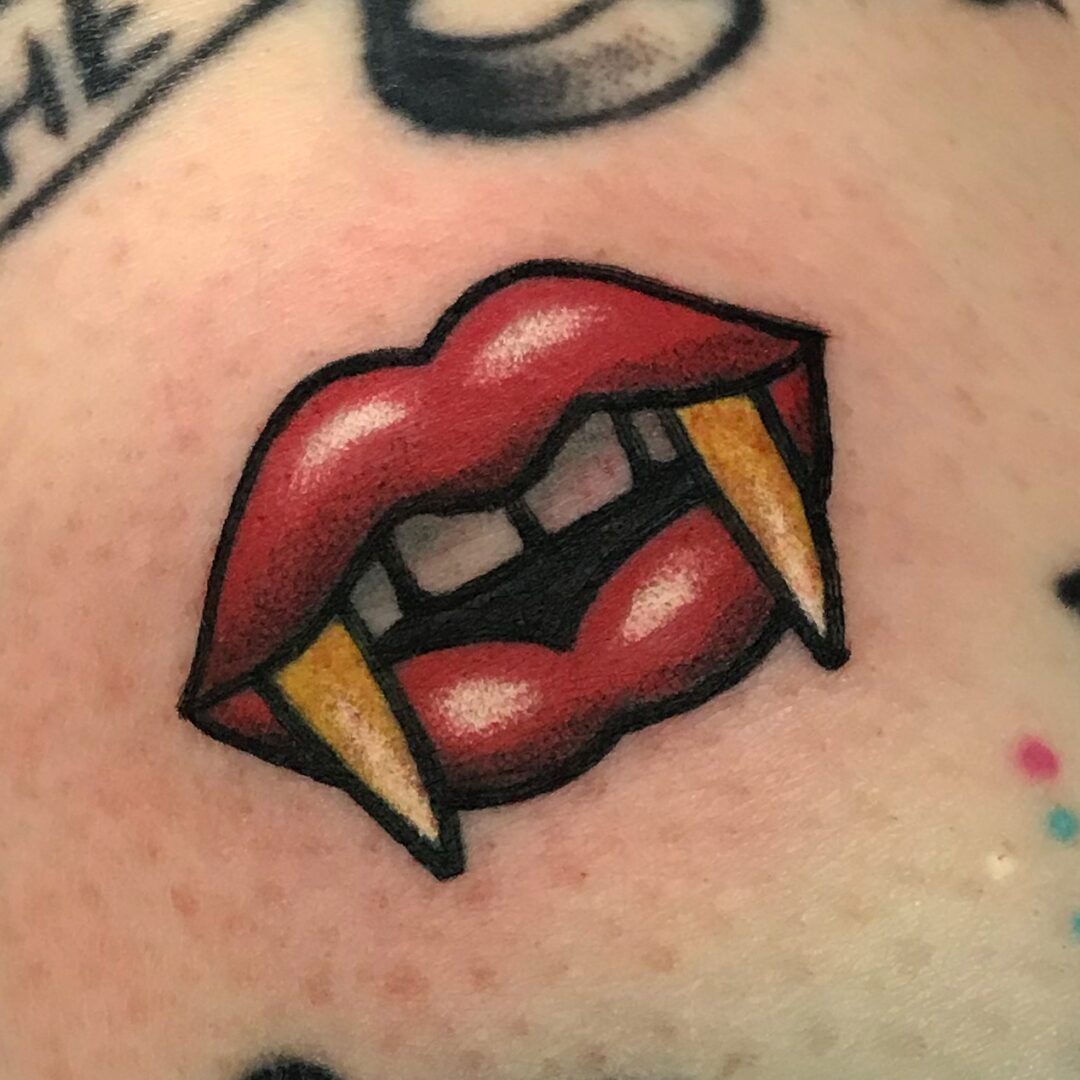 A tattoo of a red lips with yellow teeth.