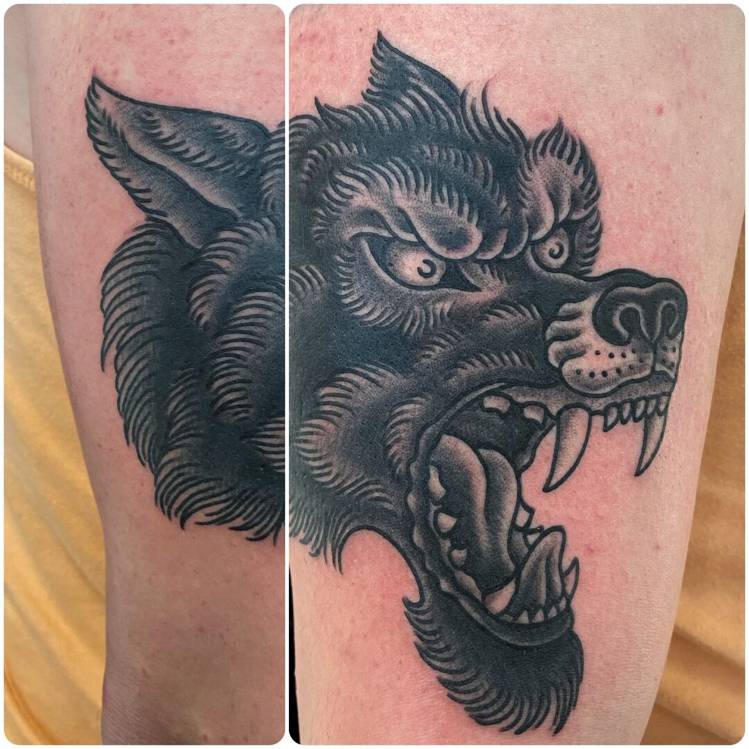 A black and grey tattoo of a wolf 's head.