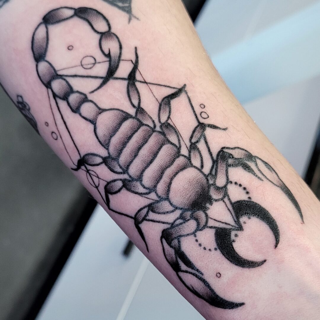 A scorpion tattoo is shown on the arm.