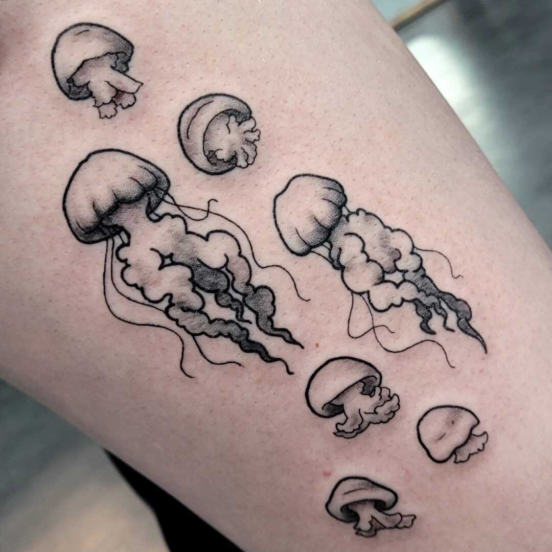 A tattoo of various types of jellyfish on the arm.