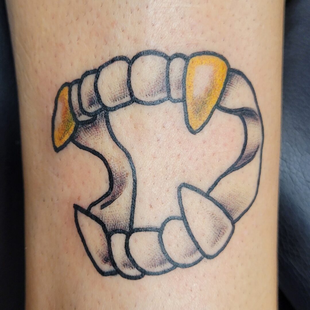 A tattoo of teeth with yellow tips on the side.