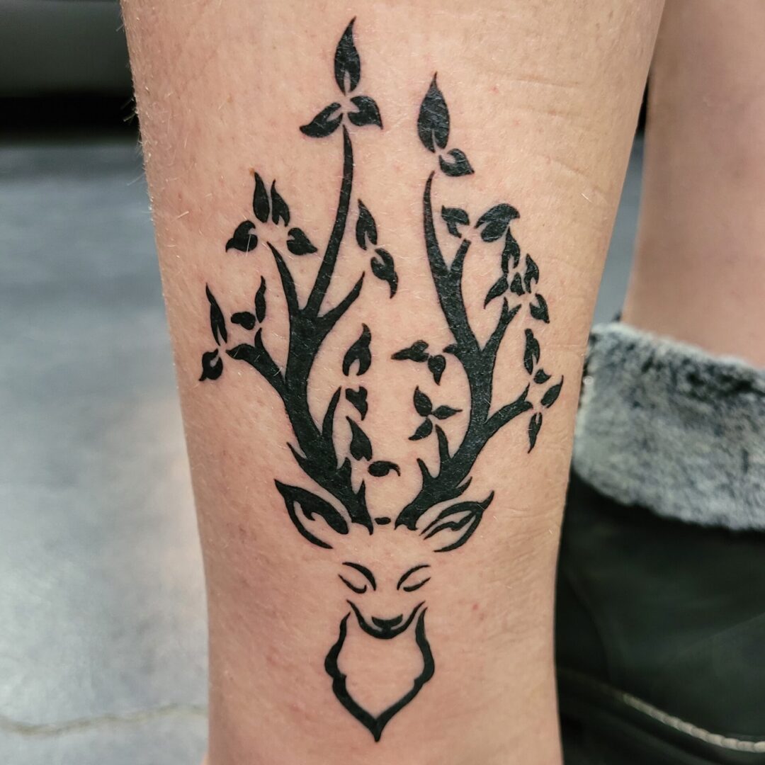 A tattoo of a deer with leaves on it's head.