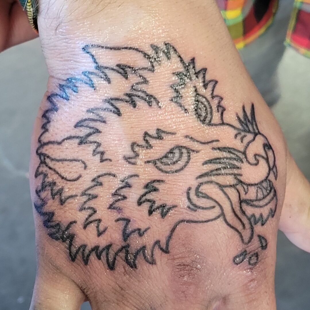 A hand with a tattoo of an animal 's head.