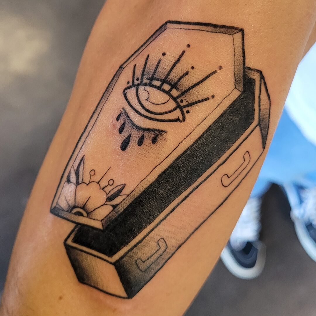 A tattoo of an open coffin with an eye on it.