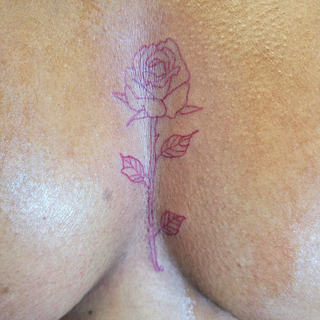 A woman 's breast with a rose tattoo on it.